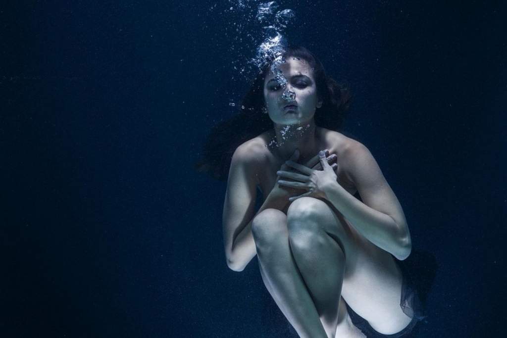 Image of a woman appearing overwhelmed—such as submerged in water, holding her chest,—symbolising the suffocating experience of anxiety.