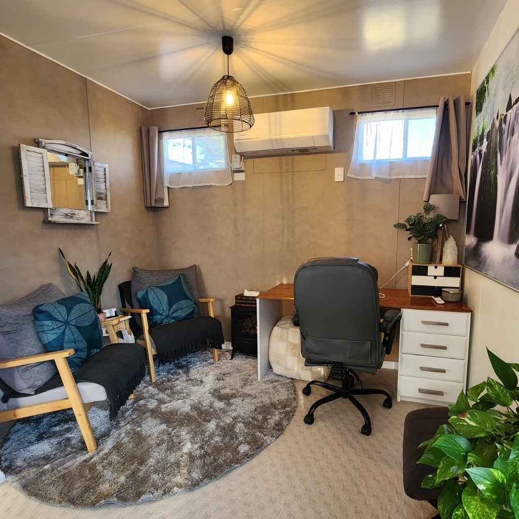 Counselling room Comfortable client seating area in a softly lit counselling room, featuring warm tones, cushions, and a peaceful atmosphere that fosters safety and trust.