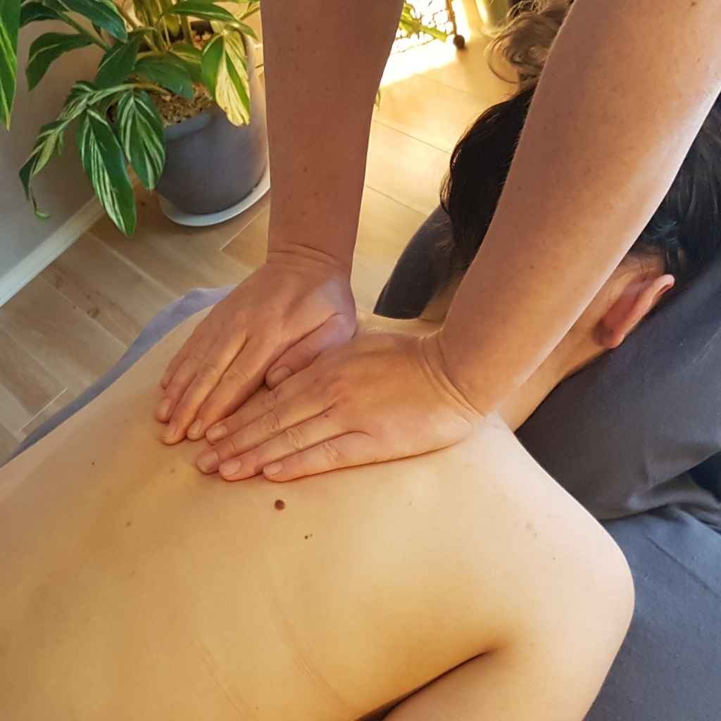 Woman receiving a welcomed back massage to relieve tension and stress Woman lying face down receiving a relaxing back massage, helping to release built-up muscle tension and ease stress.